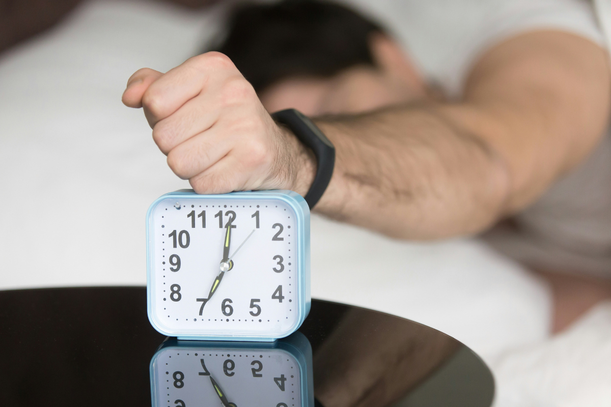Guy snoozing his alarm clock despite trying to wake up early